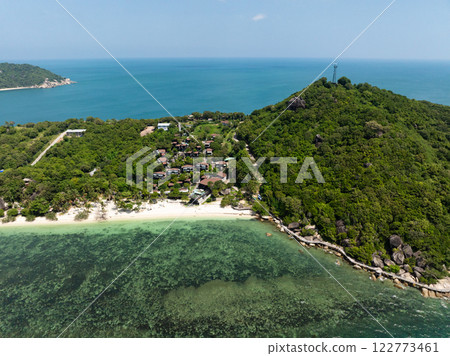A coastal view featuring turquoise waters meeting lush green hills under a sunny blue sky. Rin Nai Beach. Ko Pha Ngan, Thailand. A coastal view featuring turquoise waters meeting lush green hills under a sunny blue sky. Rin Nai Beach. Ko Pha Ngan, Thailand. 122773461