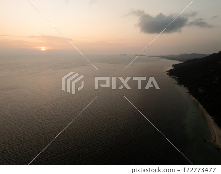 Coastline view at sunset with ocean reflecting warm colors, distant islands visible on horizon, and sky glowing. Ko Pha Ngan, Thailand. Coastline view at sunset with ocean reflecting warm colors, distant islands visible on horizon, and sky glowing. Ko Pha Ngan, Thailand. 122773477
