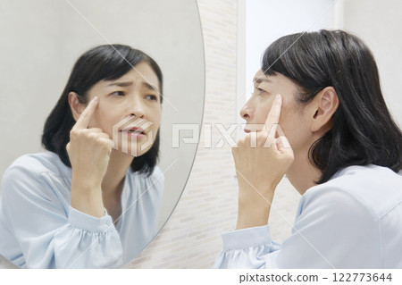 50多歲的女人擔心在鏡子裡看著自己的眼角。 122773644