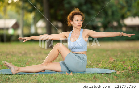 Various yoga poses performed by slender woman in fresh air in summer garden 122773750