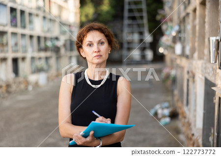 Female funeral agent filling out forms by columbarium 122773772