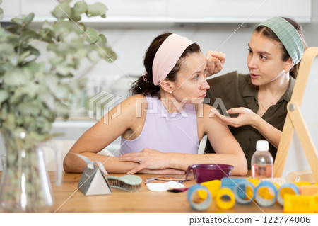 Two women looking at themselves in mirror Two women looking at themselves in mirror 122774006