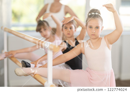 Little ballerinas together with choreography teacher in grand batman pose learn to dance ballet Little ballerinas together with choreography teacher in grand batman pose learn to dance ballet 122774024
