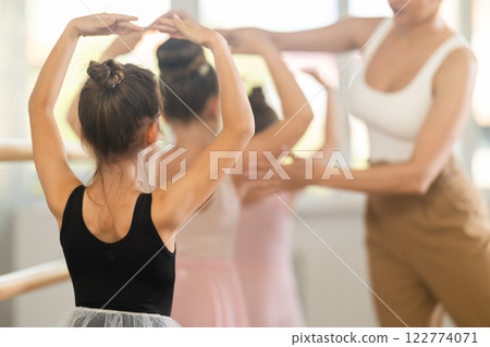 Little ballerinas learn to get into fourth position in ballet class. Choreographer helps them with this Little ballerinas learn to get into fourth position in ballet class. Choreographer helps them with this 122774071