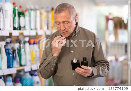 Elderly male shopper choosing scented cosmetics in supermarket Elderly male shopper choosing scented cosmetics in supermarket 122774109
