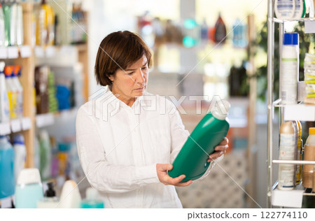 Elderly woman buyer chooses detergent in store 122774110