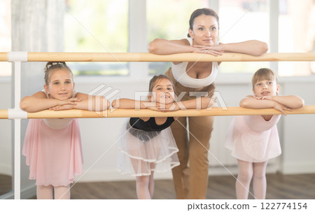 Children and female teacher pose at ballet stand bare. Children and female teacher pose at ballet stand bare. 122774154