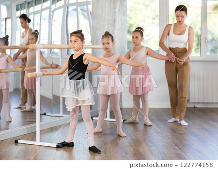 Girls in ballet class perform second position with correction of female mentor Girls in ballet class perform second position with correction of female mentor 122774158