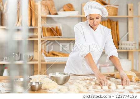 Woman works as baker in bakery, molds pies from dough, creates croissants from dough. Woman works as baker in bakery, molds pies from dough, creates croissants from dough. 122774159