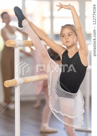 Little ballerinas together with choreography teacher in grand batman pose learn to dance ballet 122774164