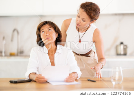 Two women discuss documents, try to solve financial problems Two women discuss documents, try to solve financial problems 122774166