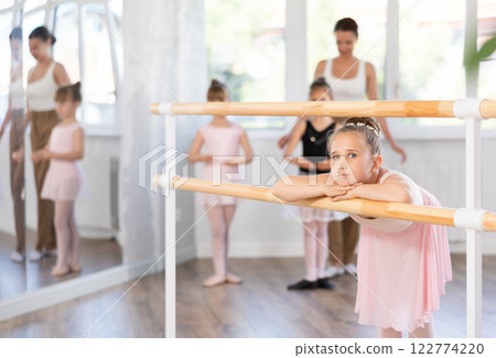 Bored girl stands near ballet stand during rehearsal, student idles in dance studio. Bored girl stands near ballet stand during rehearsal, student idles in dance studio. 122774220