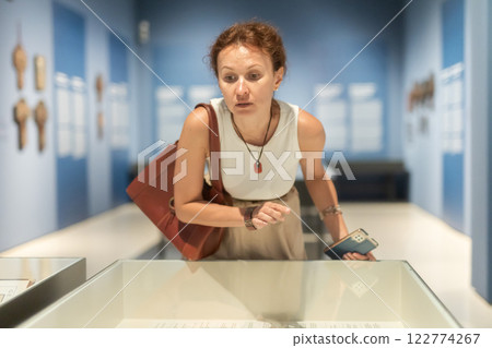 Woman with phone looking at museum exhibit Woman with phone looking at museum exhibit 122774267