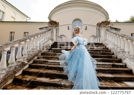 Elegant Woman in a Flowing Blue Gown Walking Down the old stone Stairs. Back view. Elegant Woman in a Flowing Blue Gown Walking Down the old stone Stairs. Back view. 122775787
