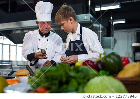 Chef teacher teaches cooking to the group children in class kitchen room. Chef teacher teaches cooking to the group children in class kitchen room. 122775946