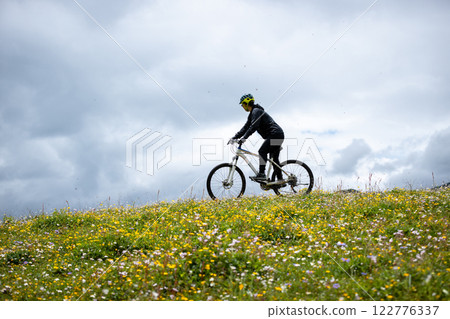 Riding mountain bike on flowering grassland mountain top 122776337