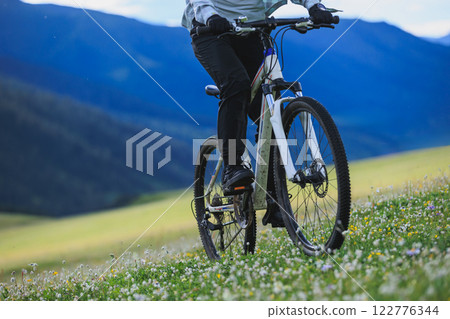 Riding mountain bike on flowering grassland mountain 122776344