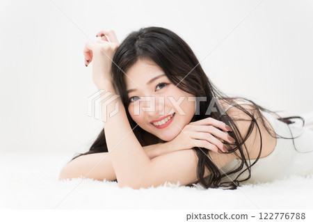 Beauty image: Smiling young woman lying down, looking at camera Beauty image: Smiling young woman lying down, looking at camera 122776788