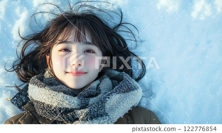 Smiling young woman lying on the snow 122776854