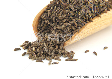 Caraway seeds spilling from wooden scoop on white background 122776941