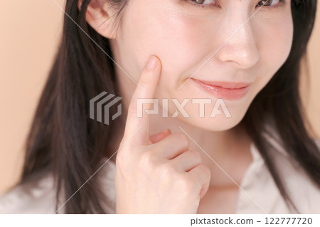 Portrait of a woman pointing at her cheek Portrait of a woman pointing at her cheek 122777720