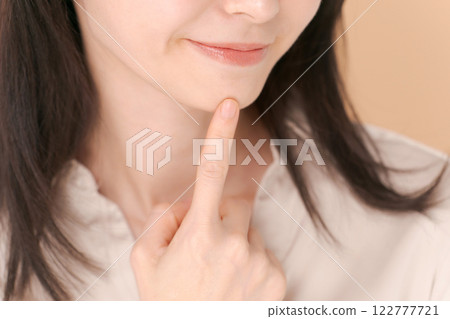 Portrait of a woman pointing at her chin Portrait of a woman pointing at her chin 122777721