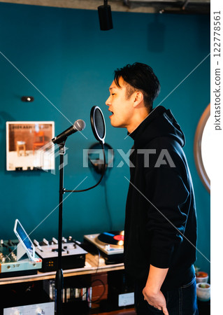 A young man recording in front of audio equipment 122778561