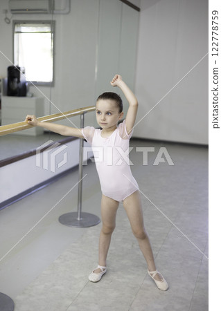 Little girl toddler ballerina in pale pink tutu and ballet shoes practicing dance moves. Child girl is studying ballet. Copy space. Ballet pump. 122778759