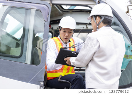 Crane driver: A man checking the work details on a tablet 122779612
