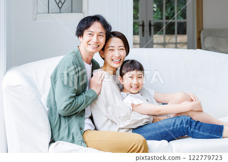 Smiling parent and child sitting on the sofa in the living room 122779723