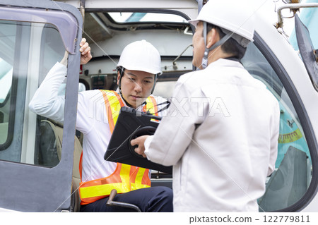 Crane driver: A man checking the work details on a tablet 122779811