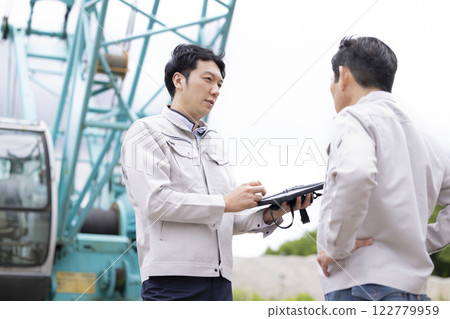 Worker working at a construction site: A man checking the work details on a tablet 122779959