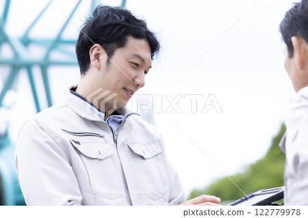Worker working at a construction site: A man checking the work details on a tablet 122779978