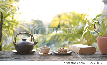 Metal tea pot and tea cup and Crispy Rice Cracker on wooden table, cozy workspace Metal tea pot and tea cup and Crispy Rice Cracker on wooden table, cozy workspace 122780123