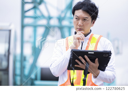 Worker working at a construction site Man holding a tablet Worker working at a construction site Man holding a tablet 122780625