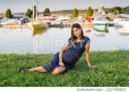 Beautiful Pregnant Woman Sitting Near Marina on Peaceful Summer Day 122780663