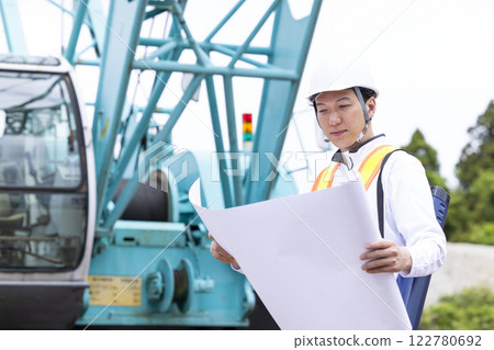 Worker working at a construction site, man looking at blueprints Worker working at a construction site, man looking at blueprints 122780692