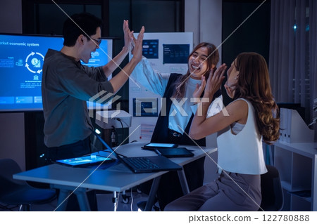 group of investor clapping hand to celebrating a successful outcome in a modern office  in front of a digital screen displaying financial data 122780888