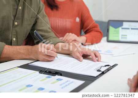 Asian couple reviewing and sign contract financial documents with the guidance of  advisor at home,collaboration and thoughtful planning for financial success 122781347