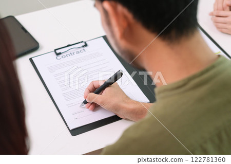 Asian couple reviewing and sign contract financial documents with the guidance of  advisor at home,collaboration and thoughtful planning for financial success 122781360