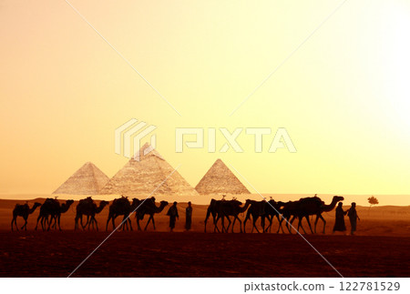 Horizontal banner with caravan of camels and Great Pyramids of Chephren and Cheops, Cairo, Egypt. People with dromedaries and three pyramids, Giza complex (Giza Necropolis). On sunrise sky background 122781529