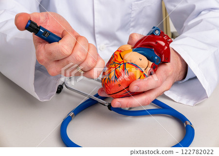 Doctor holding injection syringe and heart in hands. Heart attack, disease or vaccination concept Doctor holding injection syringe and heart in hands. Heart attack, disease or vaccination concept 122782022