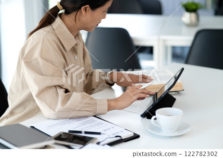 Middle-aged businesswoman sitting confidently working in the office Middle-aged businesswoman sitting confidently working in the office 122782302