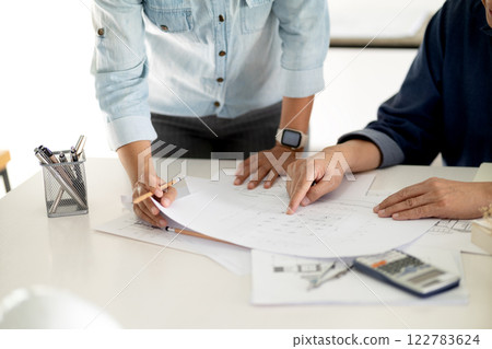 Engineers and architects are looking at the plans of the construction project consulting to plan the Engineers and architects are looking at the plans of the construction project consulting to plan the 122783624