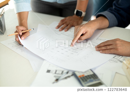 Engineers and architects are looking at the plans of the construction project consulting to plan the Engineers and architects are looking at the plans of the construction project consulting to plan the 122783648