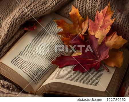 Inviting autumn display with colorful fall leaves, an open book, and a cozy knitted blanket. Relaxing reading atmosphere 122784662