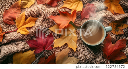 Inviting autumn scene with a steaming cup of coffee, cozy knitted blanket, and vibrant fall leaves. Ideal for relaxation 122784672