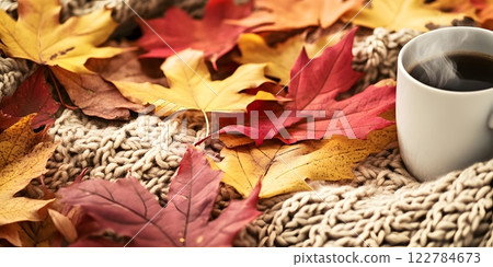 Charming autumn scene with a steaming cup of coffee, cozy knitted blanket, and colorful fall leaves. Perfect for relaxation 122784673