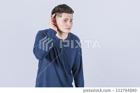Man with hand to his ear listening to something, young man tilting his ear to listen, Man with hand to his ear listening to something, young man tilting his ear to listen, 122784880