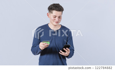Man holding credit card and cell phone, guy paying from his phone with credit card, electronic payment concept Man holding credit card and cell phone, guy paying from his phone with credit card, electronic payment concept 122784882